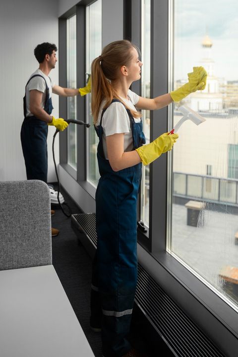 Two Blueseven cleaners in branded uniform cleaning windows together